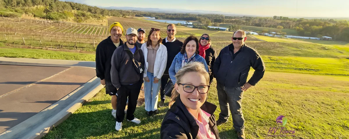 A tour group at a lookout over Hunter Valley vineyards in golden light