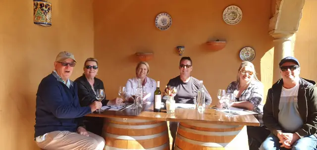 Six guests seated around barrel tables in a warm Hunter Valley tasting room