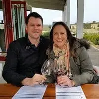 A couple toasting with red wine at a cellar door verandah table