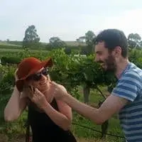 Two guests laughing together between the vines on a sunny tour day