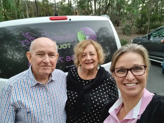 A guide with two guests in a selfie beside the signwritten tour van