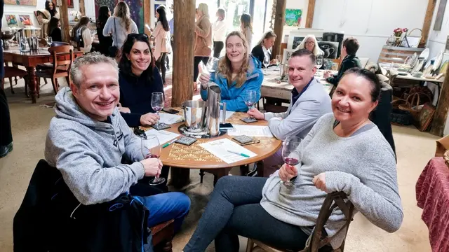 Guests sharing a tasting flight around a table at a busy cellar door