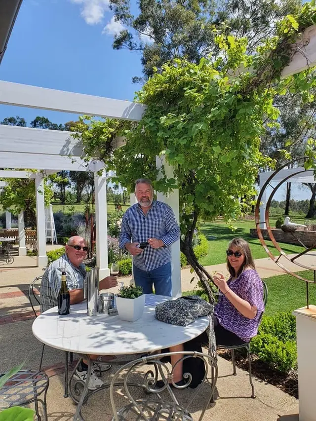 Guests gathered at a garden table under a vine-covered pergola