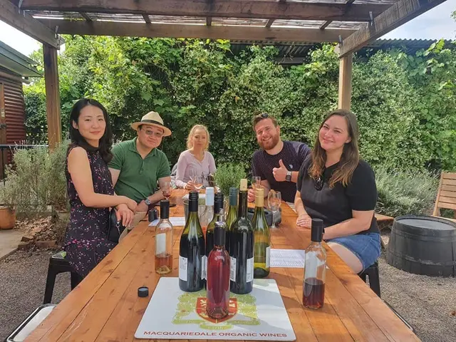 Guests at a long outdoor table lined with bottles for a tasting
