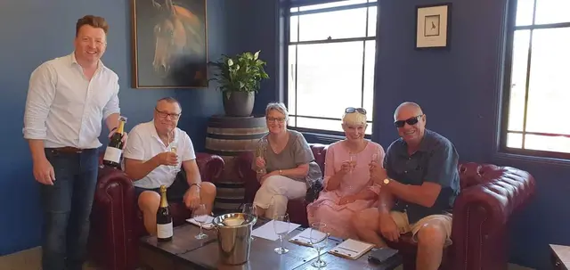 Guests seated in a cellar door lounge while a bottle is poured