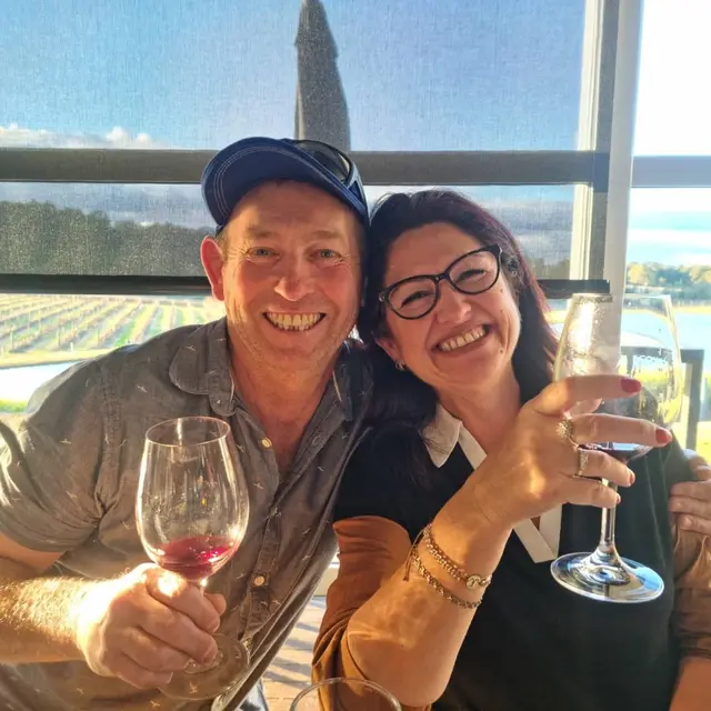 A couple's selfie with red wine and the vineyard through the window
