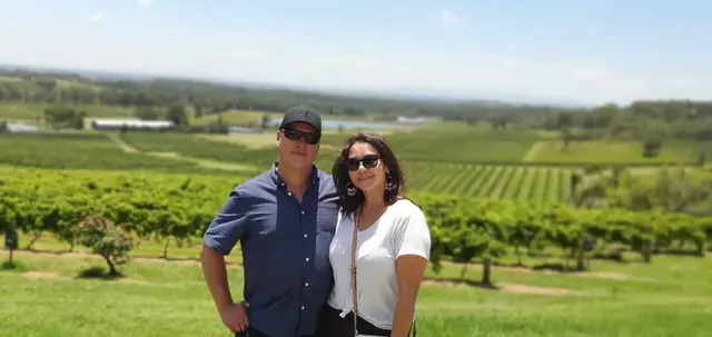 A couple in front of a wide vineyard view on a clear day