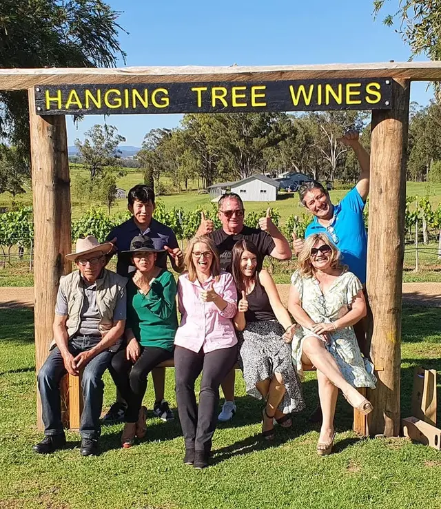 A tour group under the Hanging Tree Wines arch giving the thumbs up