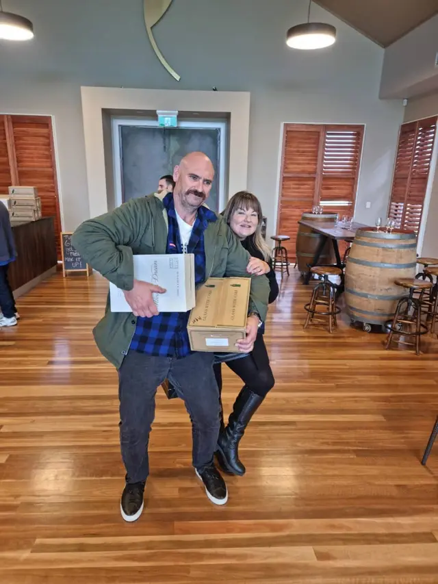 Two guests carrying home the boxes they bought at a cellar door