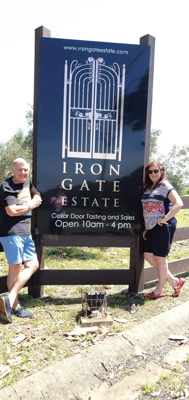Two guests beside the Iron Gate Estate cellar door sign