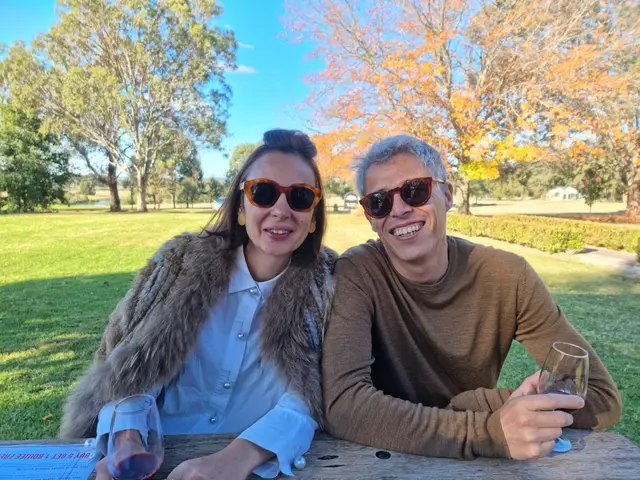 A couple at an outdoor table with autumn colour behind them