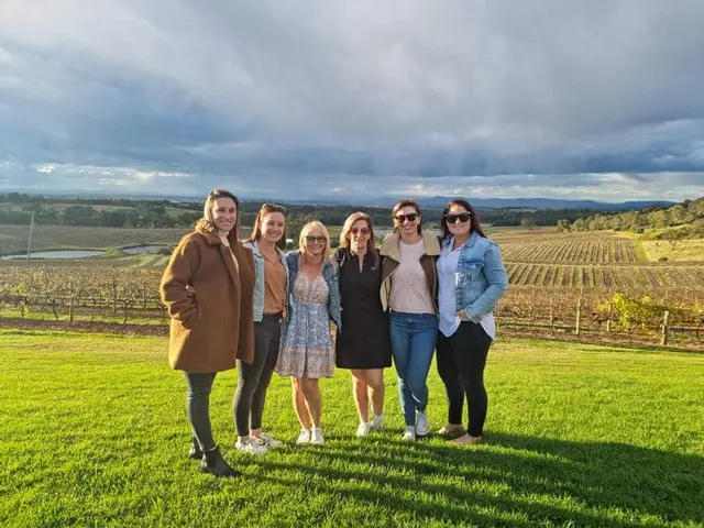 Six guests in a green vineyard under a big, moody sky