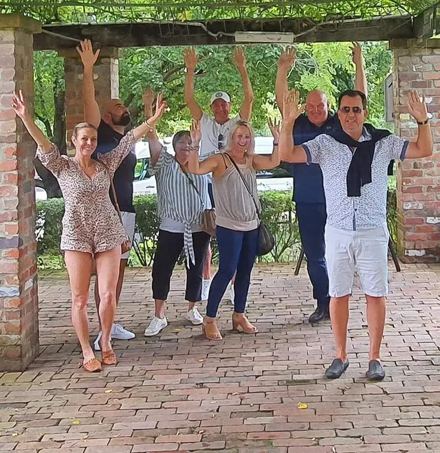 A group throwing their arms up under a brick pergola