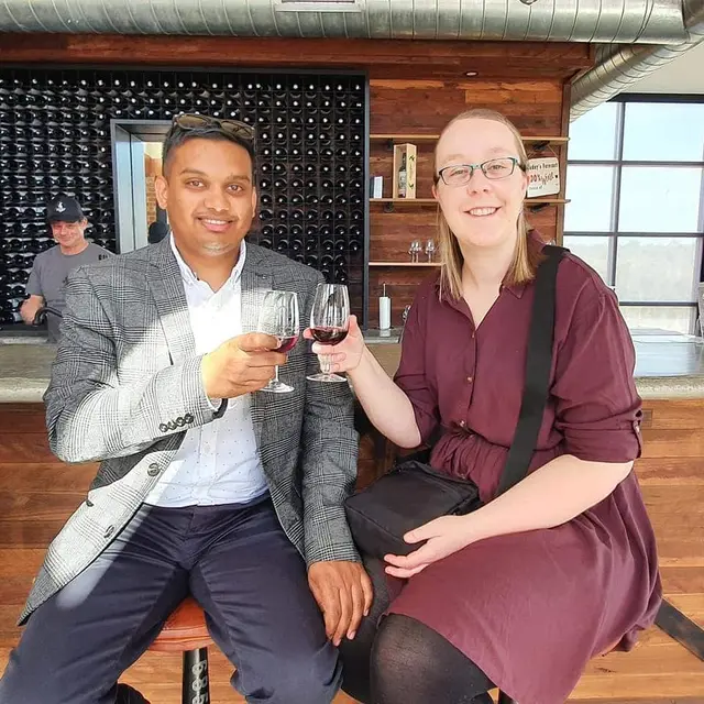 A couple with red wine in a timber-lined cellar door