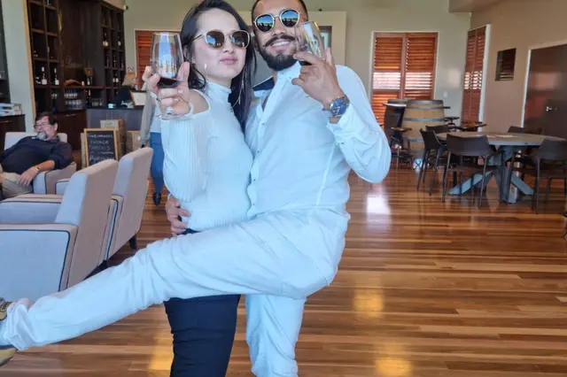 A couple mucking about with their glasses in a cellar door