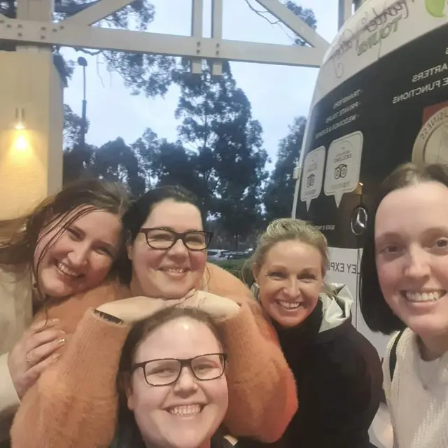 Four guests hugging in for a selfie at the end of a stop