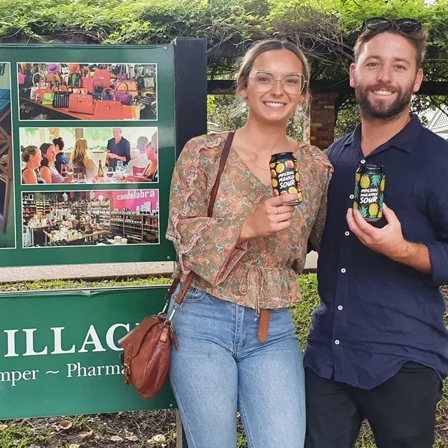 Two guests holding craft drinks outside a village cellar door