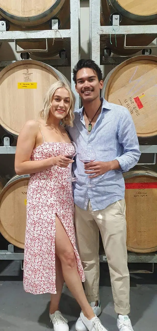 A couple in front of a stack of oak barrels