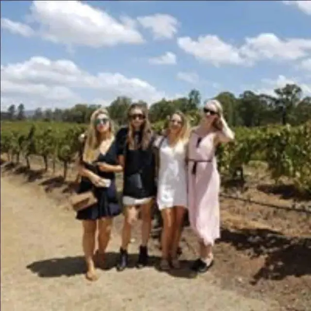 Four guests walking a vine row with their bottles