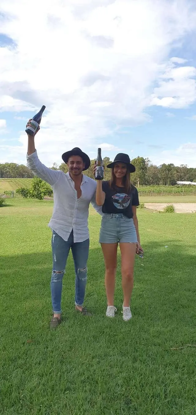 Two guests on the lawn, one holding a bottle aloft