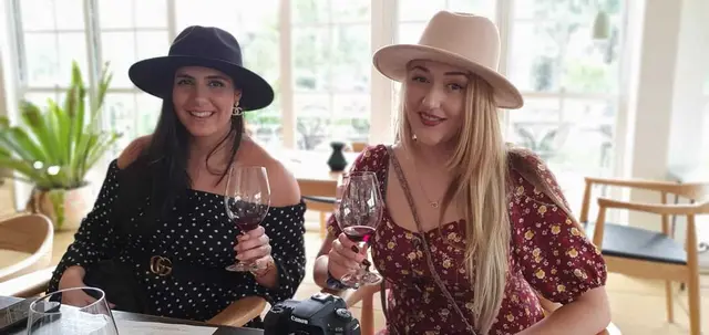 Two guests settled in with a glass of red at a garden-room cellar door