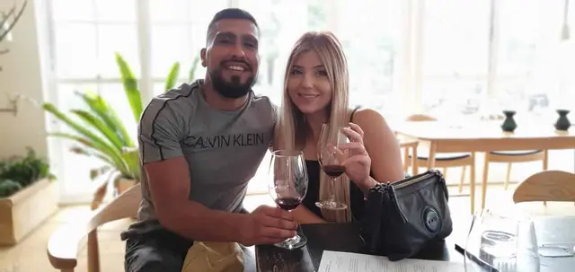 A couple with glasses of red in a bright, plant-filled tasting room