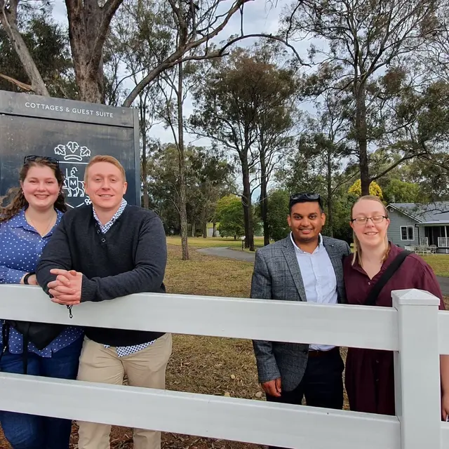 Four guests along a white post-and-rail fence