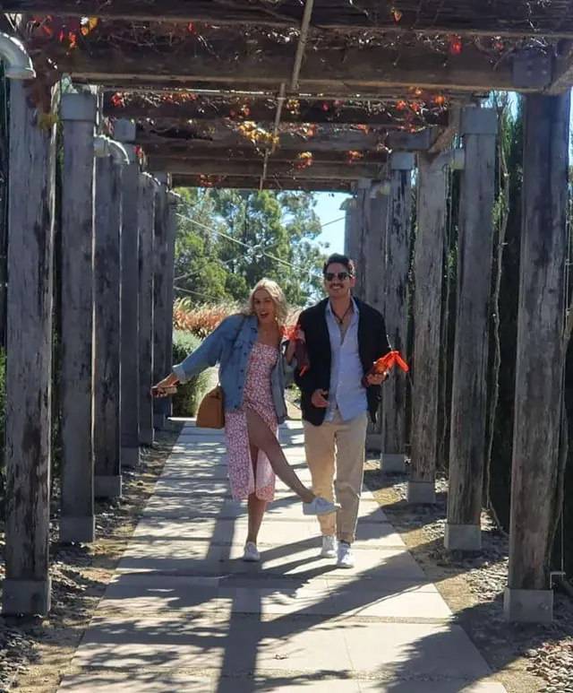 A couple walking out through a timber pergola walkway