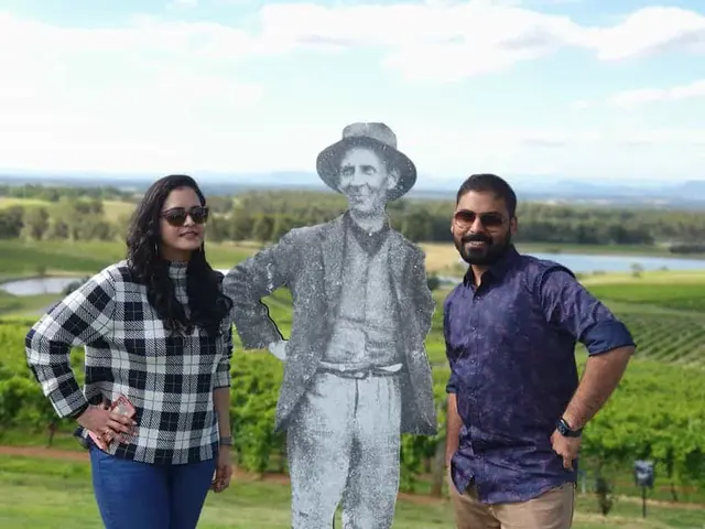 Two guests posing with the vineyard worker cut-out above the vines