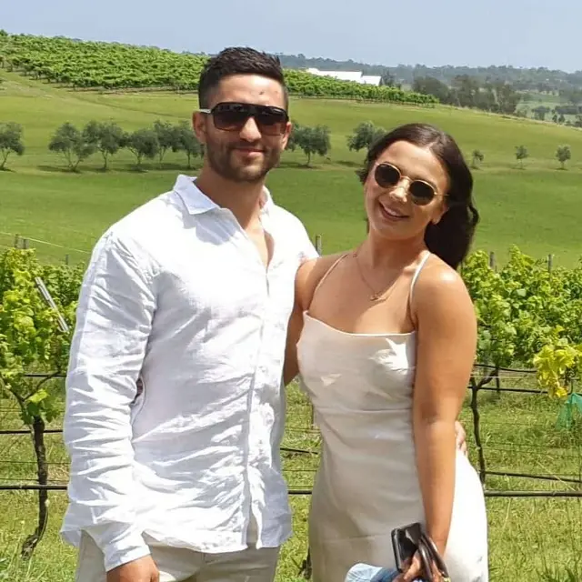 A couple in the vineyard with green hills behind