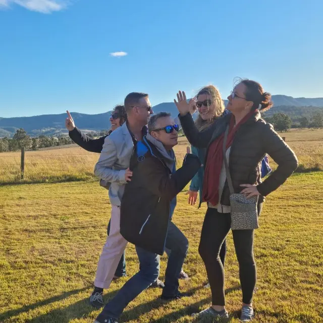 Guests larking about in a paddock with the range behind