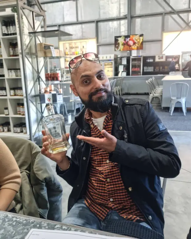 A guest presenting a bottle of gin at a distillery stop