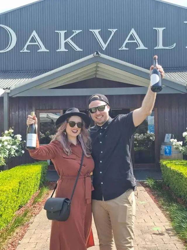 A couple holding their bottles aloft outside Oakvale