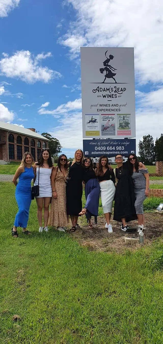 A group of guests on the lawn beside a winery sign