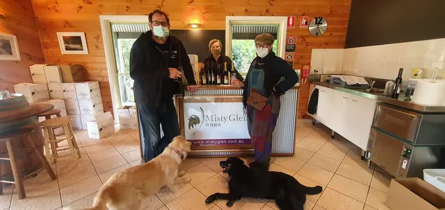 Guests with a winery sign and the two resident dogs