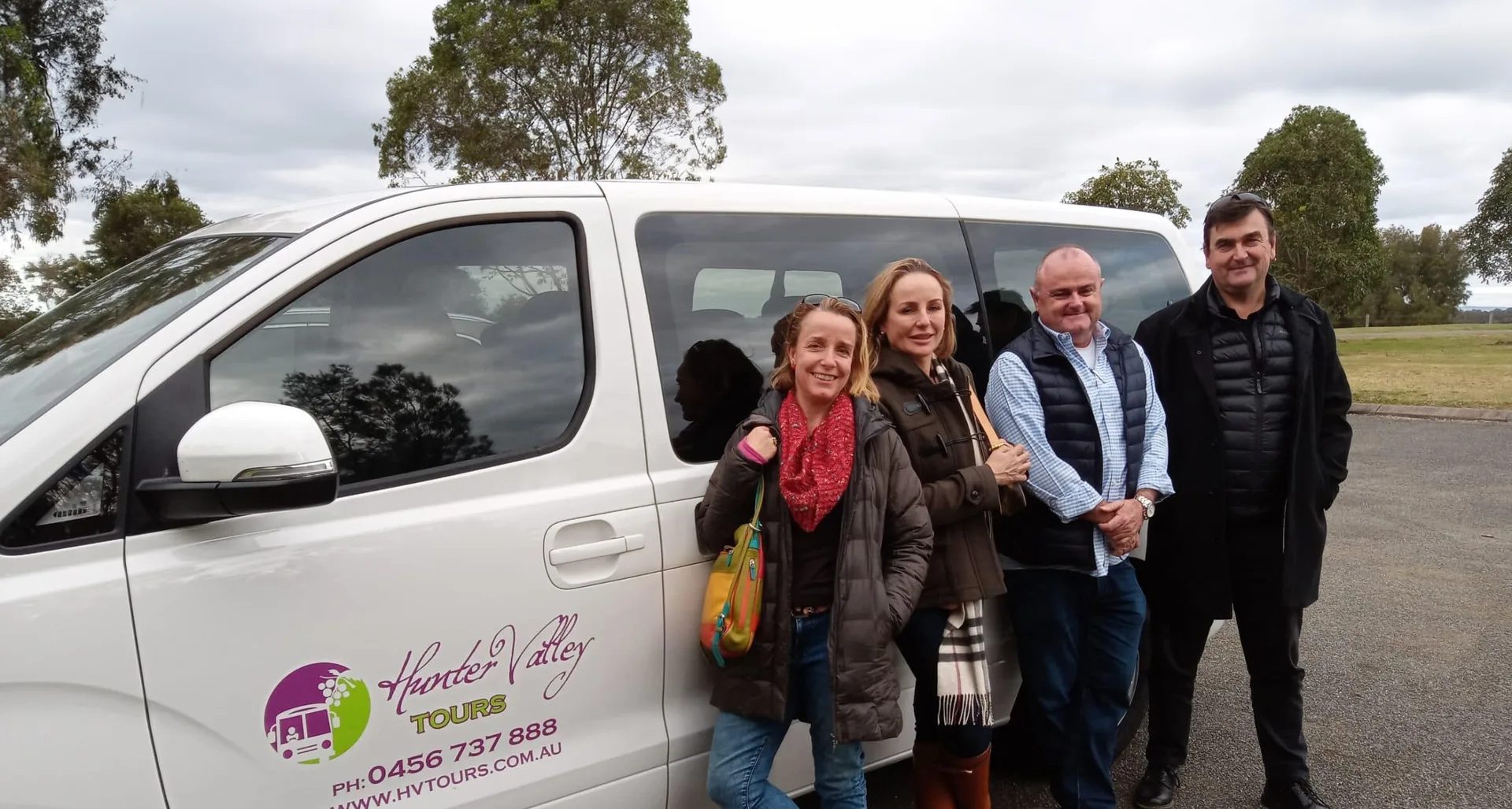 Guests standing beside the Hunter Valley Tours signwritten van before a wine tour