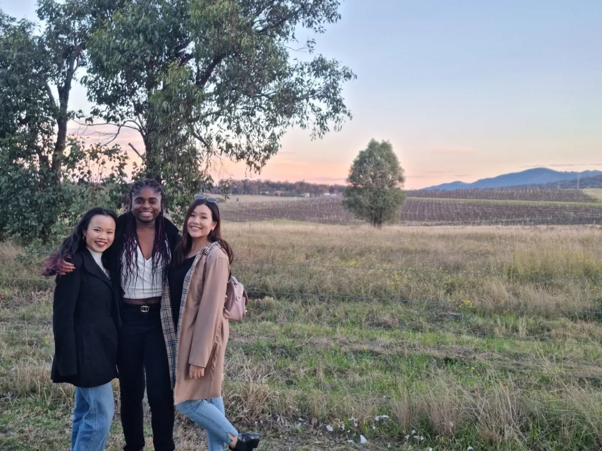 Three friends in a Hunter Valley field at dusk as the day's celebrations wind down